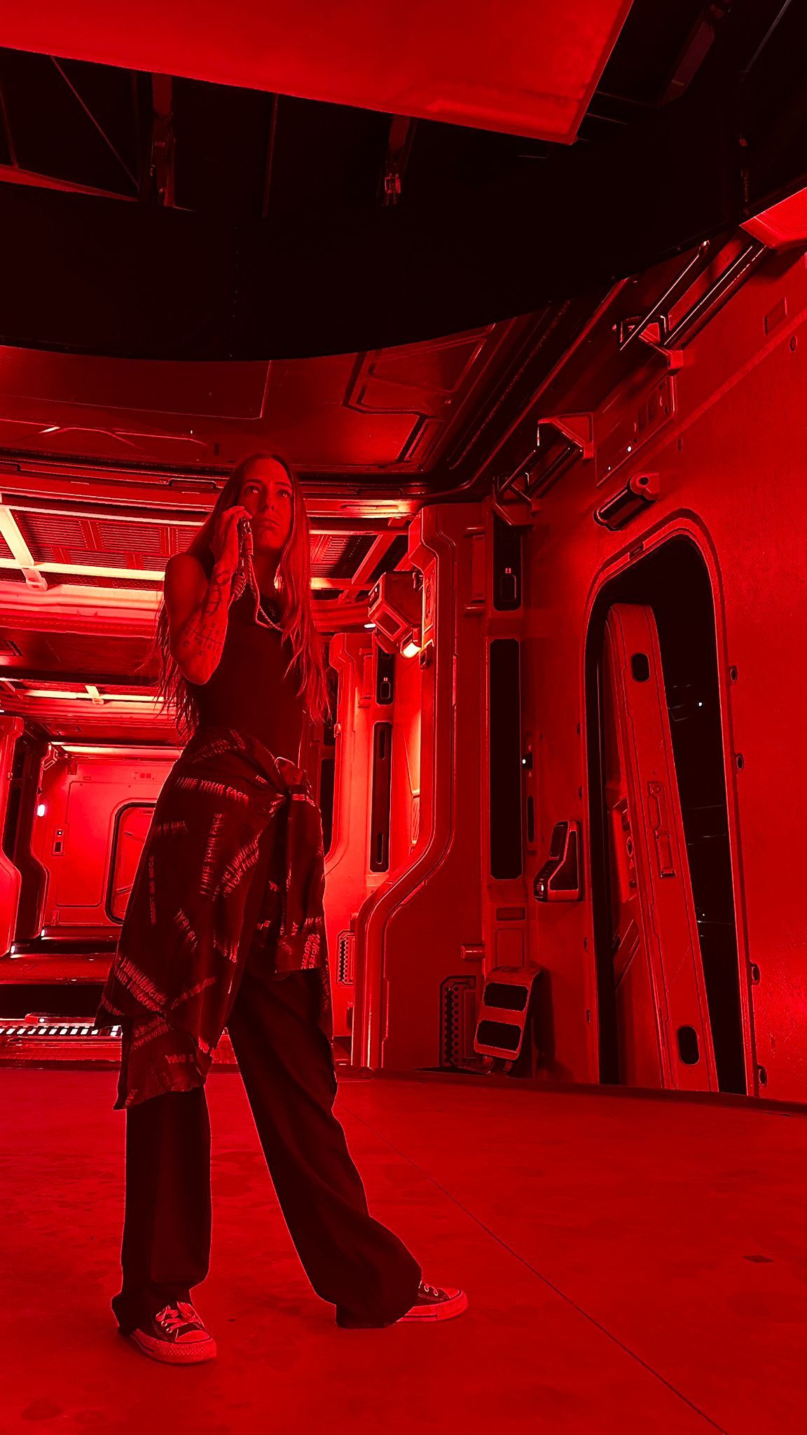 Actor in a red-lit spaceship corridor set